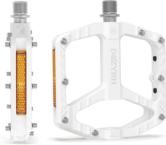 White alloy bicycle pedals with reflectors, shown on a black background.