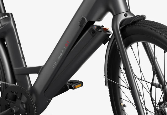 Side view of the Urtopia Carbon 1 Step Thru eBike in a modern setting, showcasing its lightweight carbon frame, step-through design, and integrated display on the handlebars.