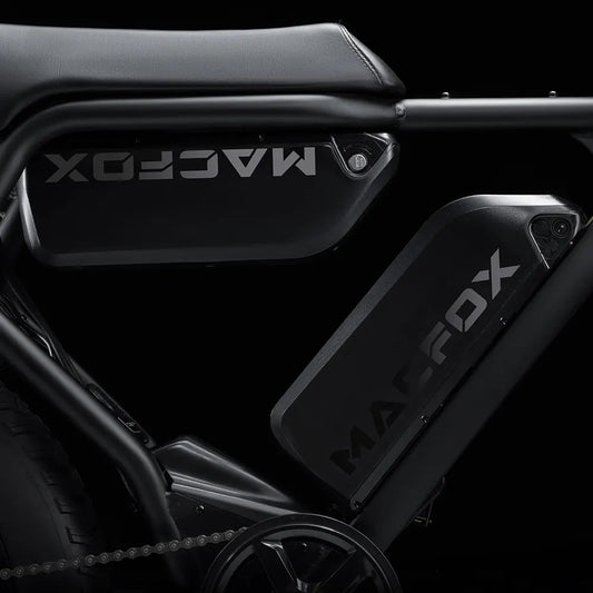 Side view of the Macfox X2 eBike in a rugged outdoor setting, showcasing its sturdy frame, fat tires, and front suspension fork.
