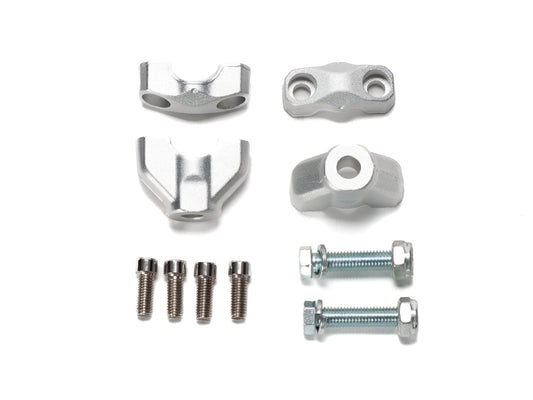 Stomp Ebox handlebar risers mounted on a motorcycle handlebar, showing silver metal construction and bolt attachments.